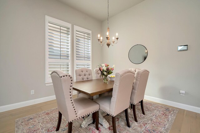 dining room with light wood-type flooring and an inviting chandelier