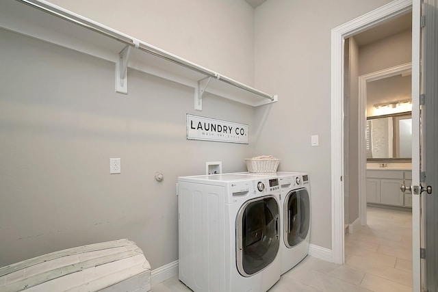 laundry area with light tile patterned floors, washer and clothes dryer, and sink