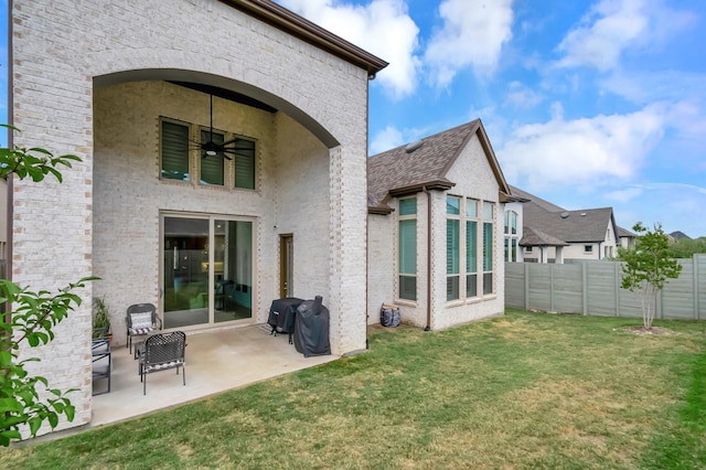 rear view of property featuring a lawn, ceiling fan, and a patio