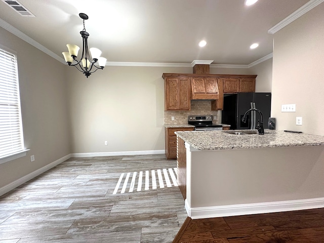 kitchen featuring sink, black fridge, kitchen peninsula, a chandelier, and stainless steel range with electric stovetop