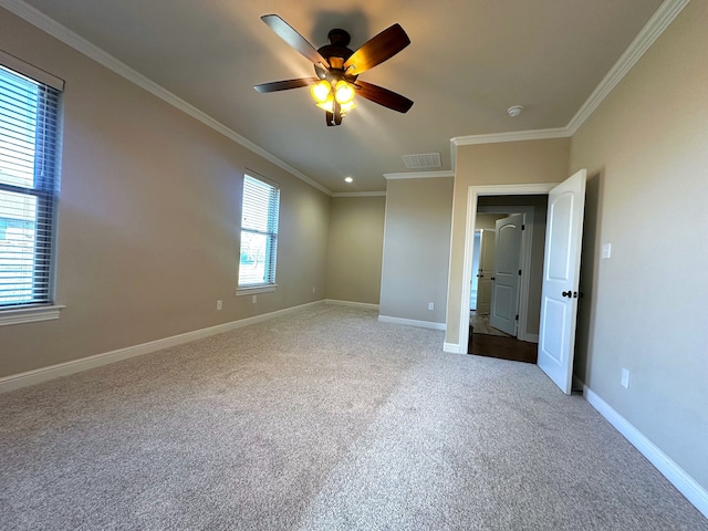 spare room with ceiling fan, crown molding, a wealth of natural light, and light carpet