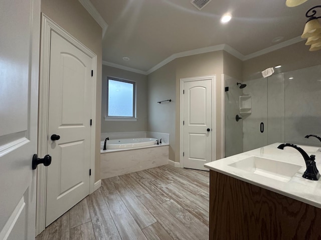 bathroom with hardwood / wood-style floors, vanity, ornamental molding, and shower with separate bathtub