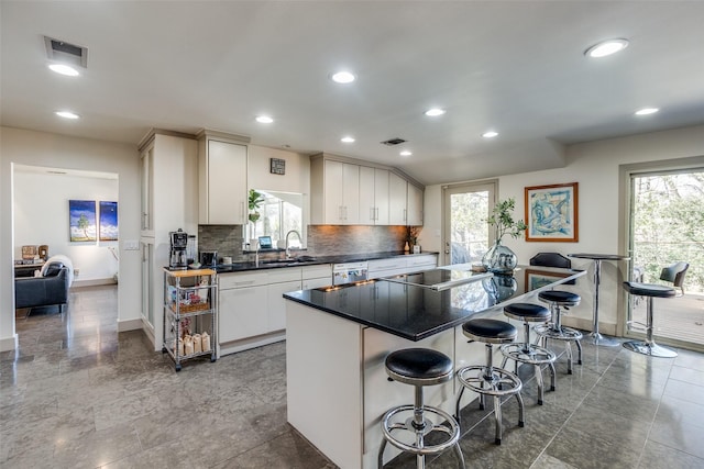 kitchen with a breakfast bar, decorative backsplash, plenty of natural light, and visible vents