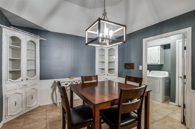 tiled dining room featuring washer / dryer, lofted ceiling, and a notable chandelier