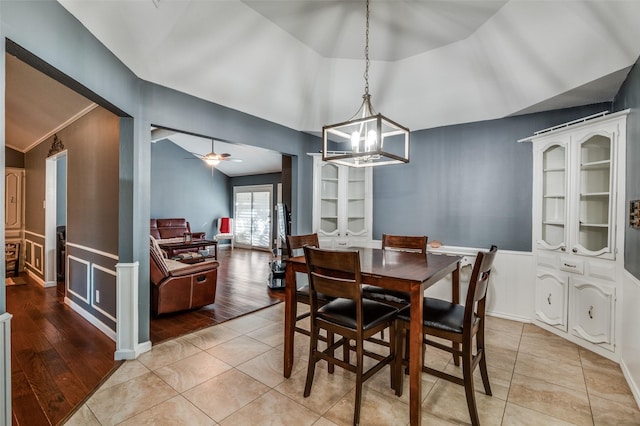 tiled dining area with ceiling fan with notable chandelier and lofted ceiling