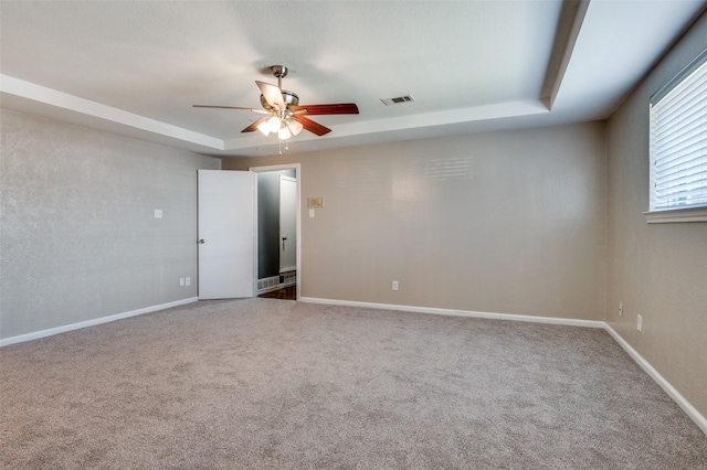 unfurnished room with a tray ceiling, ceiling fan, and carpet