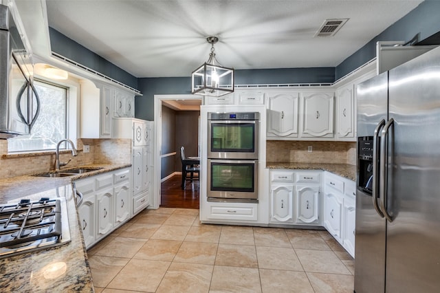 kitchen featuring appliances with stainless steel finishes, sink, a chandelier, white cabinetry, and hanging light fixtures