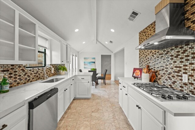 kitchen with appliances with stainless steel finishes, sink, wall chimney range hood, lofted ceiling with beams, and white cabinets