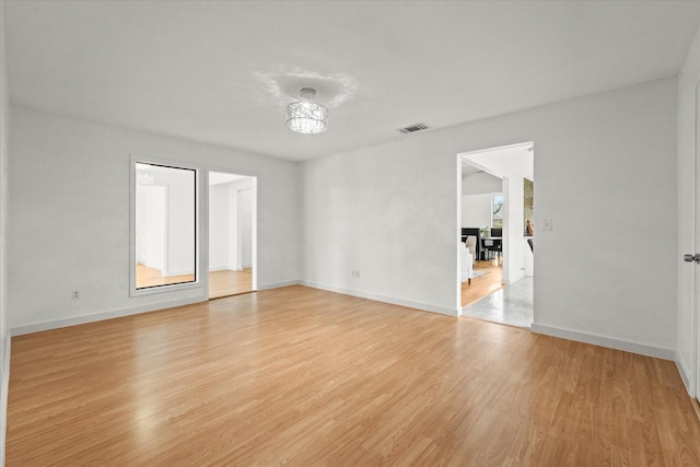 empty room featuring a notable chandelier and light hardwood / wood-style floors