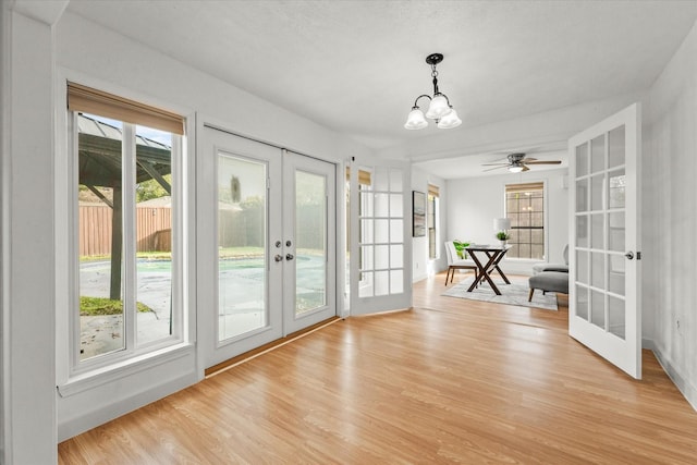 doorway to outside with ceiling fan with notable chandelier, french doors, and light wood-type flooring