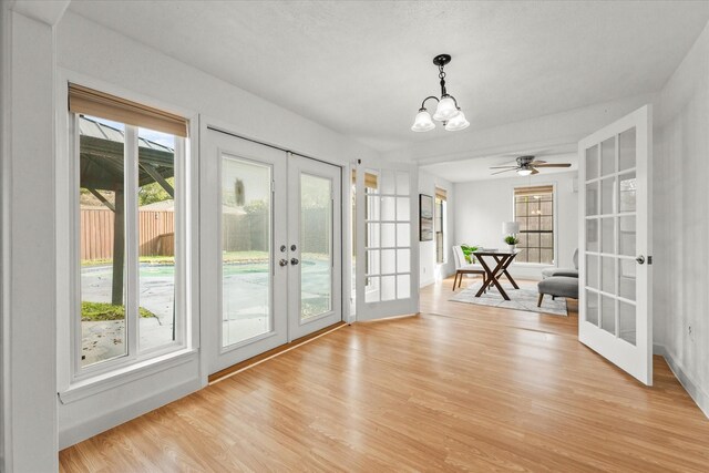 doorway with light wood finished floors, french doors, and a notable chandelier