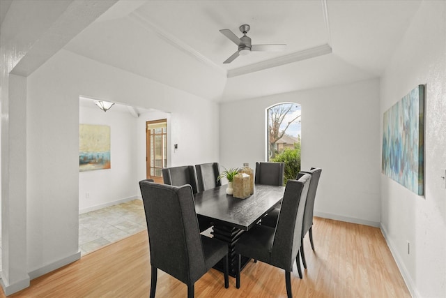 dining area featuring light wood-type flooring, a raised ceiling, ceiling fan, and ornamental molding