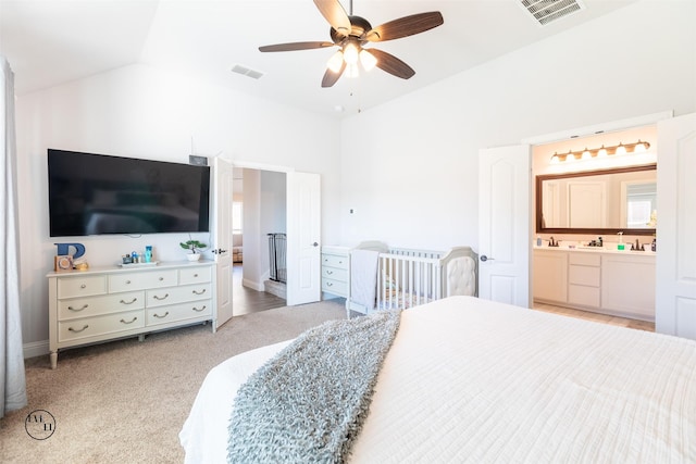 bedroom featuring ceiling fan, vaulted ceiling, light carpet, and ensuite bath