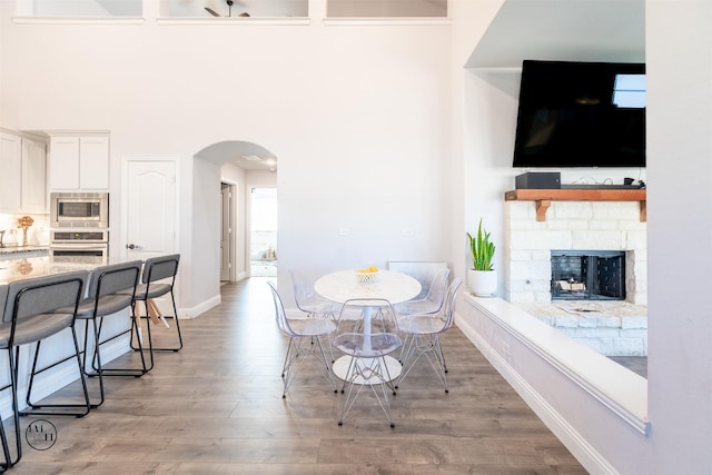 dining area featuring a fireplace, a high ceiling, and light wood-type flooring