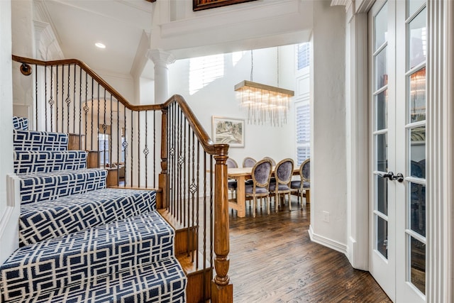 stairs featuring hardwood / wood-style floors, ornate columns, french doors, and an inviting chandelier