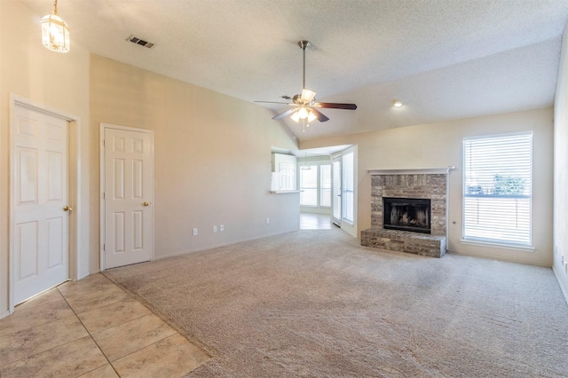 unfurnished living room with ceiling fan, a brick fireplace, light carpet, and a textured ceiling