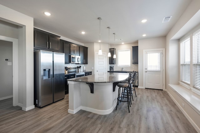 kitchen featuring decorative backsplash, appliances with stainless steel finishes, a center island, and pendant lighting