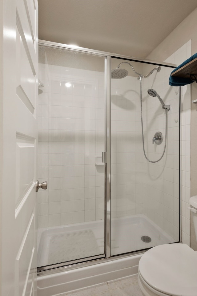 bathroom featuring a shower with shower door and toilet