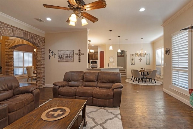 living room with ceiling fan with notable chandelier, hardwood / wood-style flooring, and ornamental molding