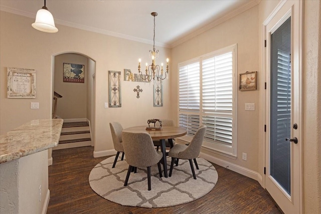 dining space featuring dark wood-type flooring, ornamental molding, and an inviting chandelier