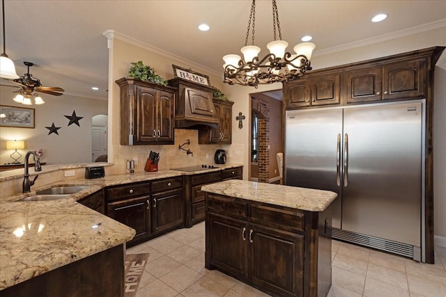 kitchen featuring stainless steel built in fridge, pendant lighting, dark brown cabinets, and sink