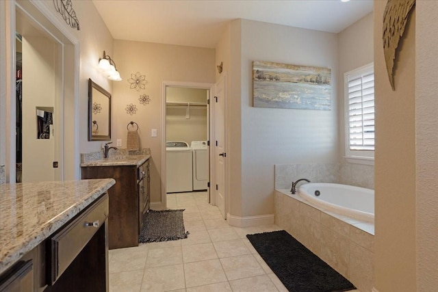 bathroom featuring independent washer and dryer, vanity, tiled bath, and tile patterned floors