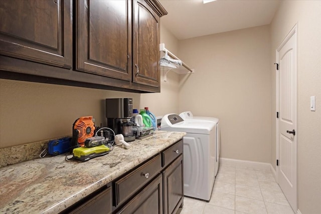 laundry area featuring washing machine and clothes dryer, light tile patterned floors, and cabinets