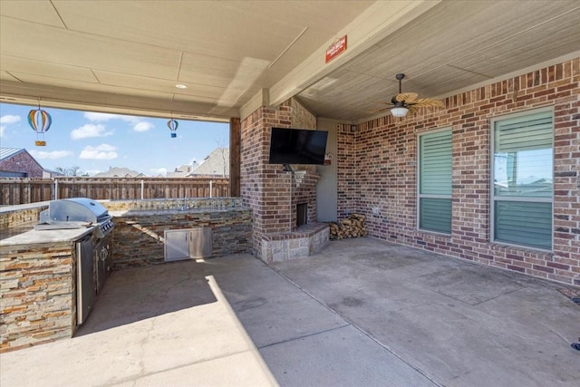 view of patio / terrace with an outdoor brick fireplace, a grill, ceiling fan, and an outdoor kitchen