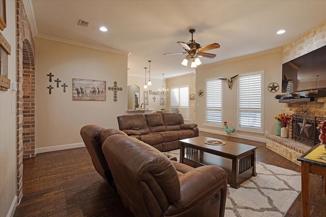 living room featuring dark hardwood / wood-style floors, ceiling fan, ornamental molding, and a fireplace