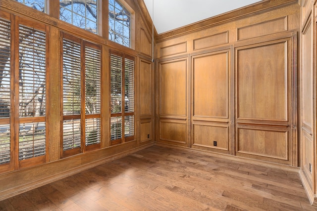 interior space with hardwood / wood-style floors, high vaulted ceiling, and wood walls