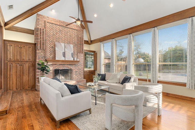 living room with a fireplace, beam ceiling, ceiling fan, and hardwood / wood-style floors