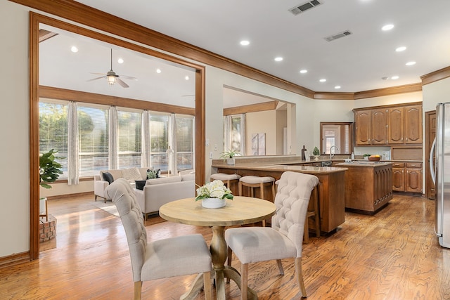 dining room featuring light hardwood / wood-style flooring, ceiling fan, crown molding, and sink