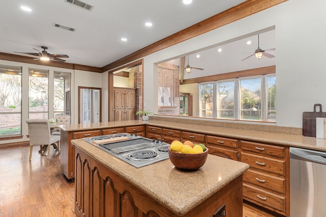 kitchen with a center island, ornamental molding, a wealth of natural light, appliances with stainless steel finishes, and light hardwood / wood-style floors