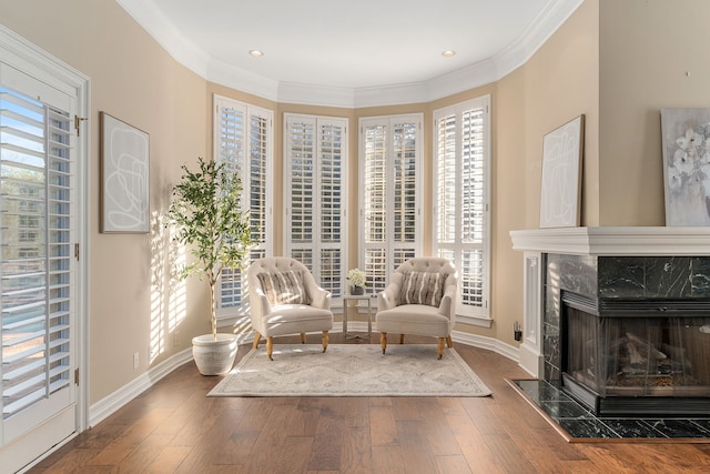 living area featuring hardwood / wood-style floors, ornamental molding, and a premium fireplace