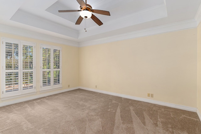 empty room with a tray ceiling, ceiling fan, crown molding, and light colored carpet