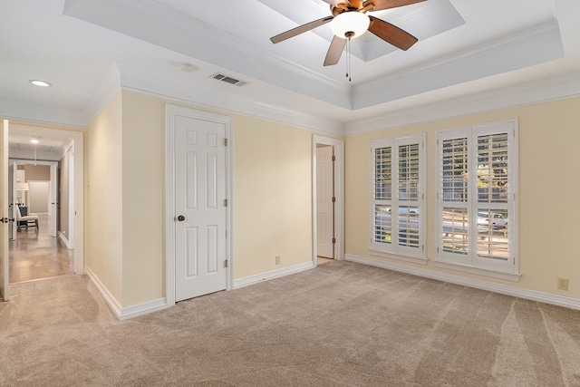 unfurnished bedroom with a tray ceiling, crown molding, ceiling fan, and light colored carpet