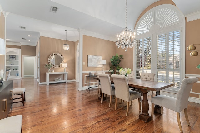 dining room featuring crown molding, hardwood / wood-style floors, a chandelier, and built in features