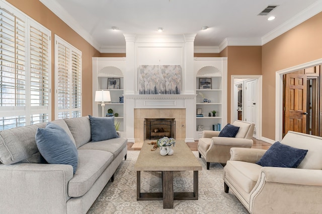 living room with a tiled fireplace, crown molding, and light hardwood / wood-style flooring