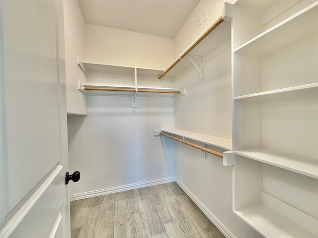 walk in closet with light hardwood / wood-style flooring