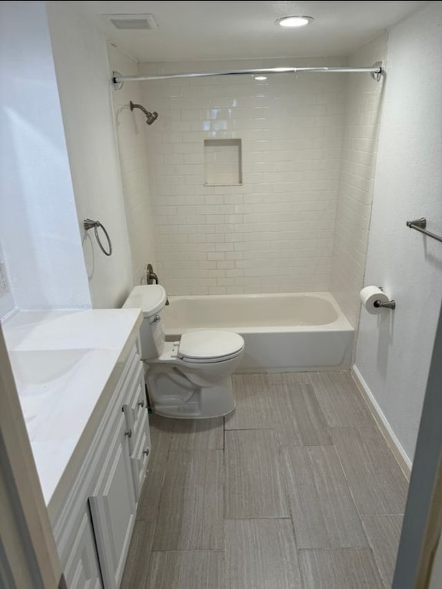 full bathroom featuring tiled shower / bath, vanity, and toilet