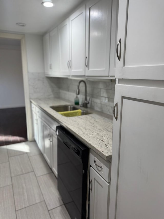 kitchen featuring white cabinetry, dishwasher, light stone countertops, sink, and tasteful backsplash