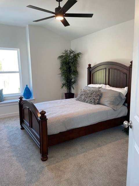 carpeted bedroom with ceiling fan and lofted ceiling