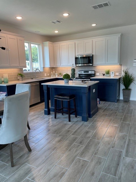 kitchen with a kitchen breakfast bar, sink, a kitchen island, white cabinetry, and stainless steel appliances