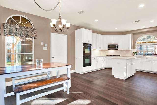 kitchen featuring decorative backsplash, gas stovetop, double oven, decorative light fixtures, and white cabinetry