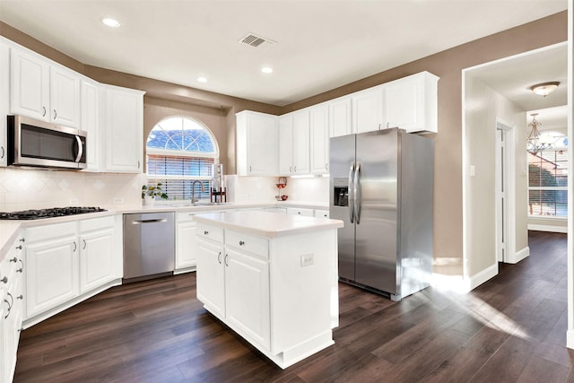 kitchen with white cabinets, a center island, stainless steel appliances, and dark wood-type flooring