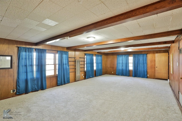 carpeted spare room with wooden walls and beamed ceiling