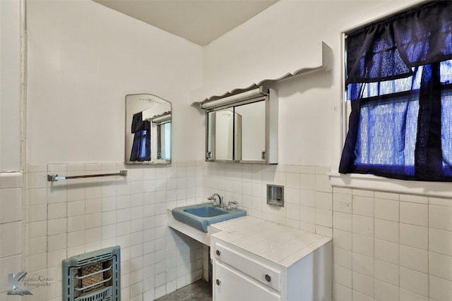 bathroom with heating unit, sink, and tile walls