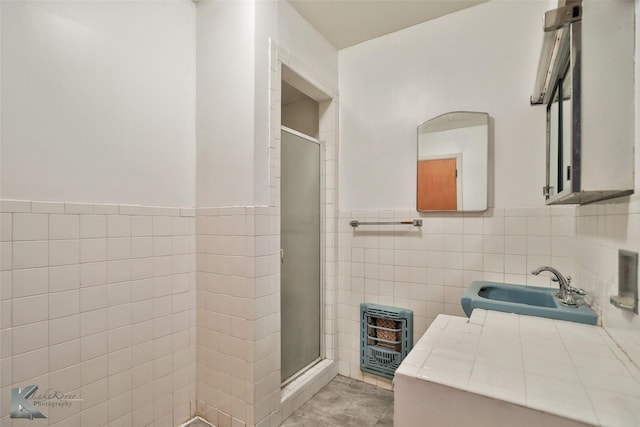 bathroom featuring an enclosed shower, tile walls, sink, and heating unit