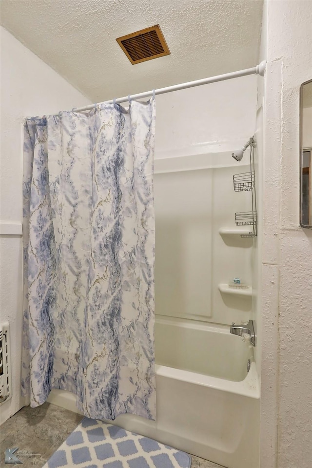 bathroom featuring shower / bath combo, a textured ceiling, and heating unit