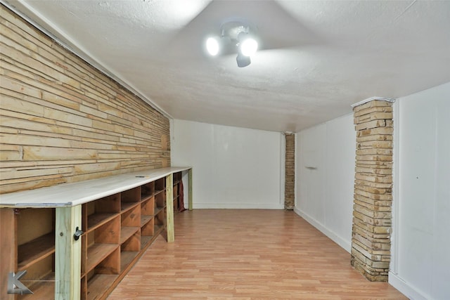 additional living space featuring a textured ceiling, wooden walls, and light hardwood / wood-style flooring